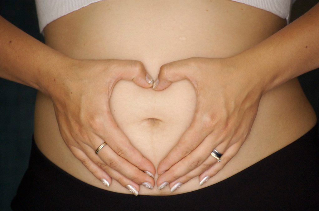 Zwei Hände formen ein Herz auf einem Babybauch (Symbolbild).